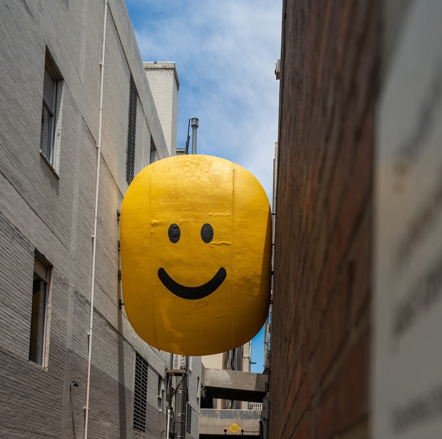 A giant smiley face balloon caught between two buildings